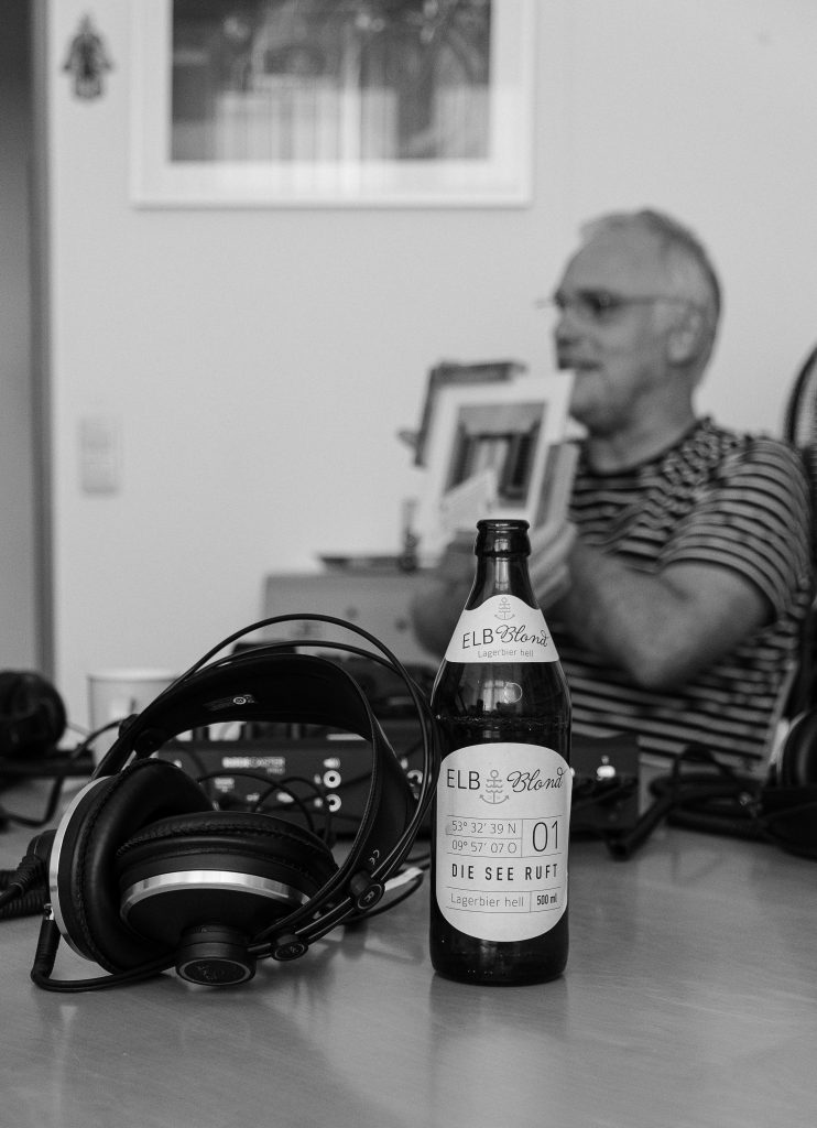 Bierflasche aus Harburger Brauerei im Vordergrund - unscharf im Hintergrund Christoph mit Bild in der Hand